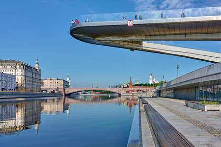 Moscow - 15 may 2021: "Soaring bridge" with people above Moscow river in the park "Zaryadye". Day landscape with view at embankment Moscow river and Kremlin with reflections in water.のeditorial素材