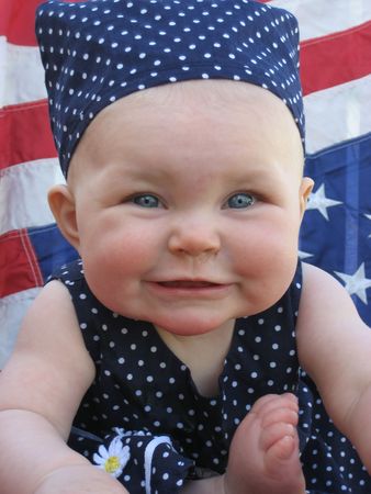 Adorable baby girl with blue Adorable baby girl with blue and white dress and American flag background.の写真素材