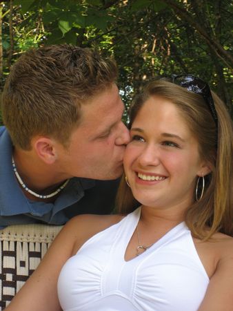 Man leaning in over a chair to kiss his girlfriend.の写真素材