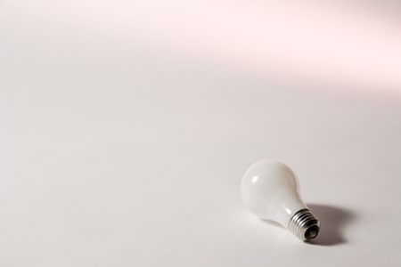 Light bulb on empty set with a pink light across the background. Enough space in the image for any wording to be added.の写真素材