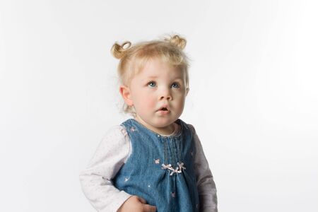 Adorable young girl looking up. She has pigtails. On a white background.の写真素材