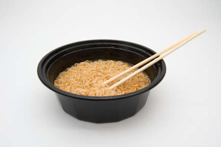 noodles in black takeout bowl with chopsticks isolated on whiteの写真素材