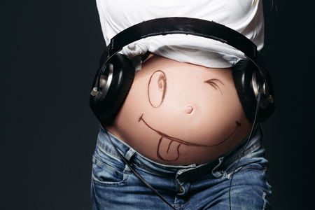 Pregnant female with big earphones on tummy.の写真素材