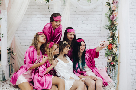 Pretty bridesmaids with bride taking selfie at hen party.の写真素材