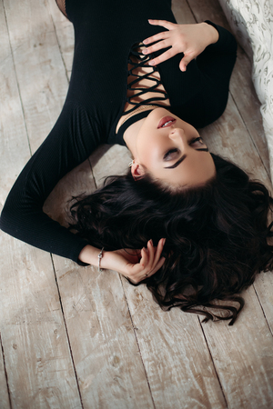 Above view of beautiful brunette woman in black lying on floor.の写真素材