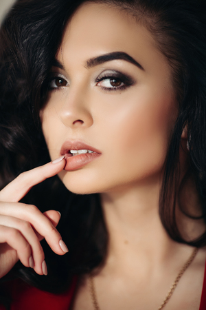 Beautiful woman in red seductive touching lips by hand.の写真素材