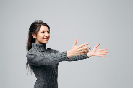 Smiling pretty brunette trying catch something Isolated on gray backgroundの写真素材