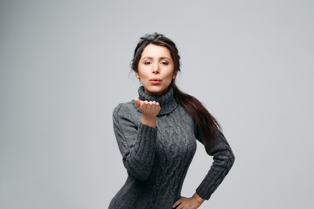 Beautiful charming brunette sending air-kiss Isolated on gray backgroundの写真素材