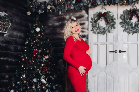 Sensuality pregant woman embracing stomach standing against decorated home.の写真素材