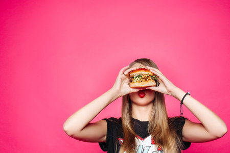 Hungry girl biting burger of chicken and saladの写真素材
