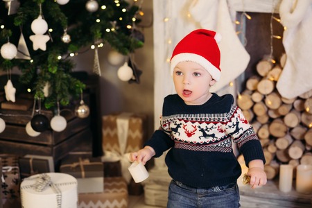 Little blonde boy playing with Christmas presents and boxes.の写真素材