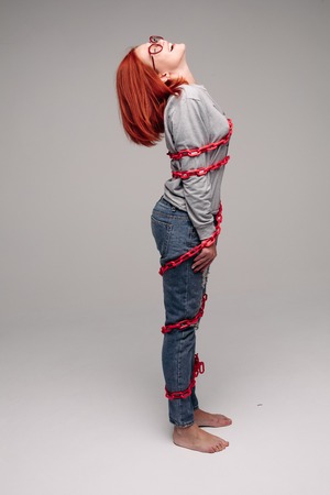 girl entangled in a chain,A red-haired woman with brown hair tries to get rid of the chainの写真素材