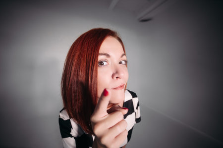 Close up of young pretty lady in black and white blouse looking at camera and holding her finger up.