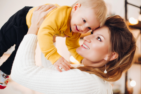 Lovely mother rising up her baby and smiling to each other.の写真素材