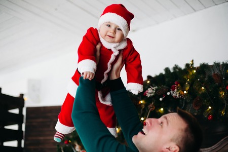 Cheerful boy laughing and playing with parent in christmas studioの写真素材