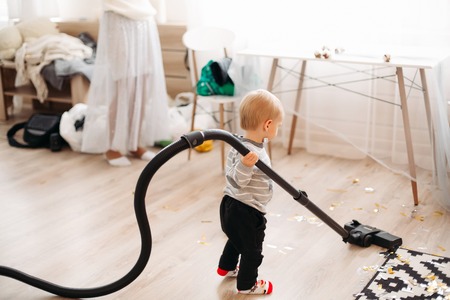 Blonde little boy in gray sweater and black jeans lying on roof among confetti.の写真素材