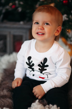 Lovely baby with deer on jersey sitting in artificial snow at Ch