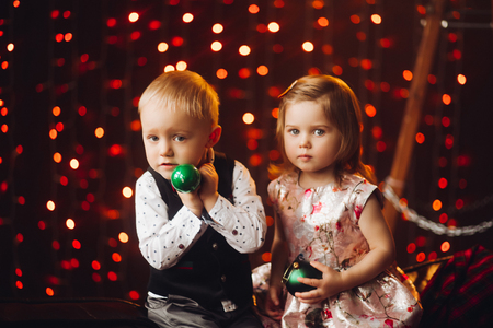 Two little kids playing with green Christmas bows near decoration and Christmas tree.の写真素材