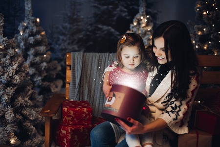 Loving happy mom with baby looking inside Christmas presentの写真素材