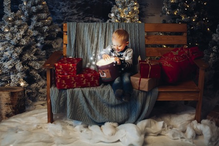 Smiling lovely baby d sitting on bench with lots of christmas presents.の写真素材