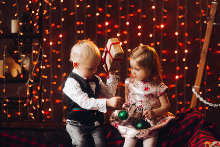 Two little kids playing with green Christmas bows near decoration and Christmas tree.の写真素材