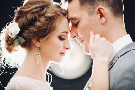 Gorgeous bride and handsome groom touching by faces each other.の写真素材