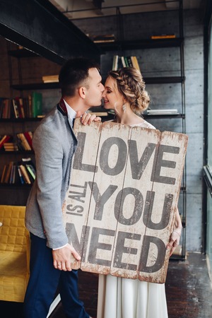 Loving couple kissing holding signboard all you need is love.の写真素材