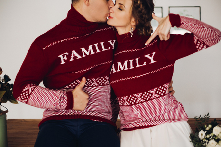 Couple in red sweaters having fun together and pointing by fingers.の写真素材