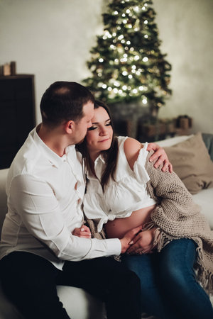 Couple sitting on sofa with tea cups in hands.