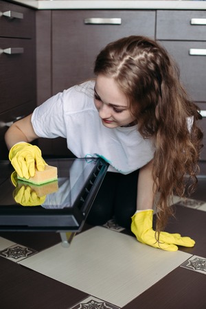 Woman, wearing in protective glove with rag cleaning oven at kitchen.の写真素材