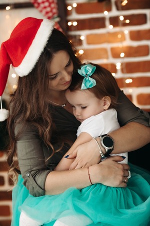 Woman holding cute daughter, posing in studio.の写真素材