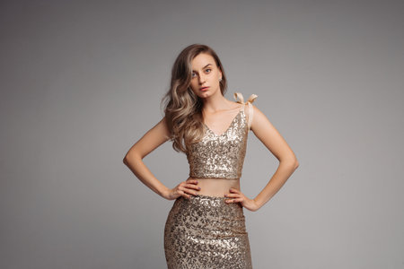 Slim model in sexy beige dress looking at camera and posingの写真素材