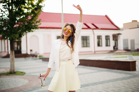 Pretty trendy girl with braid in mirrored sunglasses drinking coffee in the street.の写真素材