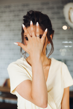 Brunette bride showing hand with wedding ring and hiding face.の写真素材