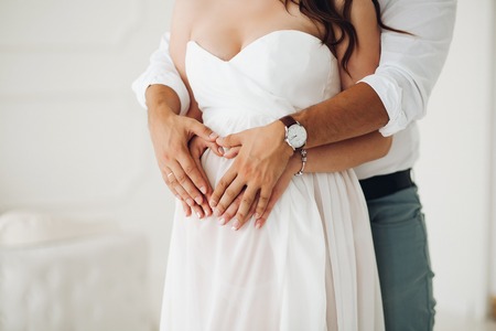 Man hugging his wife belly in white dress.の写真素材