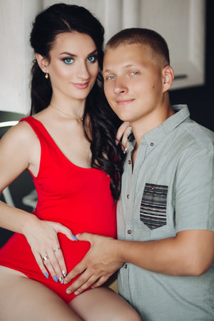 Caring husband kissing pregnant wife while cooking dinner