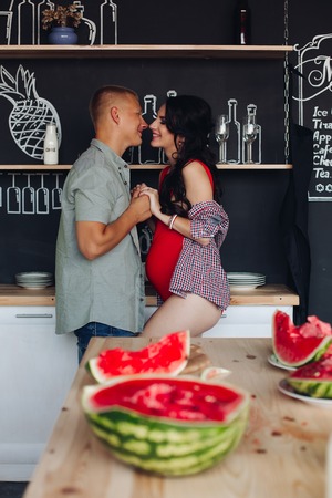 Pregnant brunette wife looking at blonde handsome husband.の写真素材