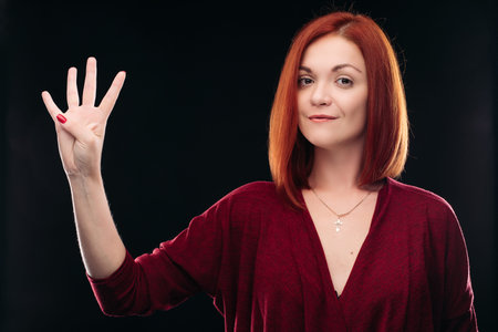 Attractive red haired girl holding hand with 4 finger up.