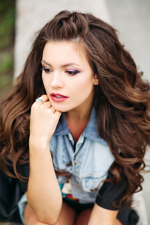 Stylish, beautiful hipster brunette sitting at street.の写真素材