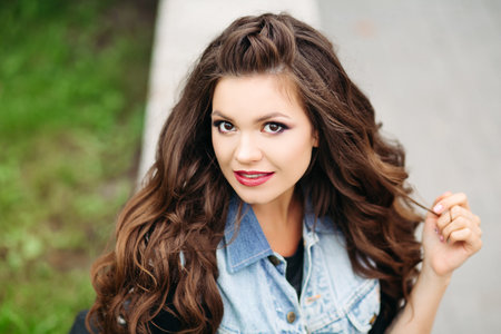 Stylish, beautiful hipster brunette sitting at street.の写真素材