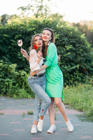 Two fashionable and positivity girls eating  sweet candies on stick.の写真素材