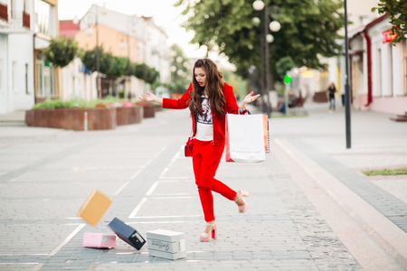 Fashionable woman in red suit with shopping bags dropped shoe boxes in the street.の写真素材