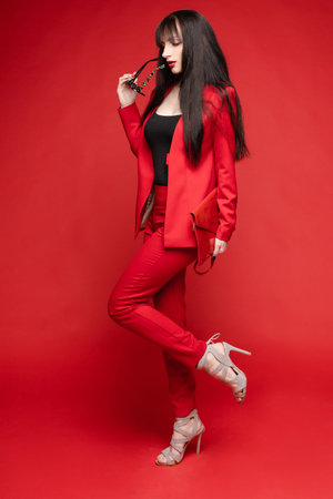 Side view of glamorous brunette posing in red smart suitの写真素材