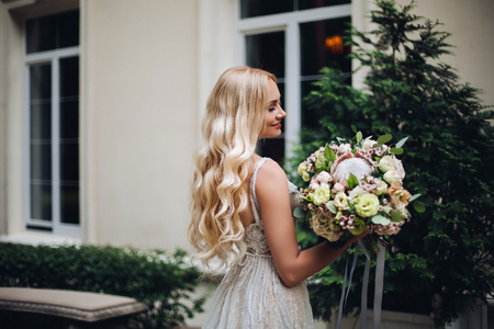 Gorgeous bride with wedding flowers boquet posing outdoors, against luxury house.の写真素材