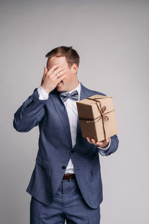 This present is for you Part of man in suit showing present box with smile while standing against white backgroundの写真素材