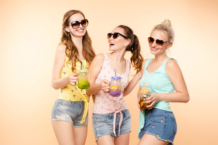 Three sporty girls drinking fresh juice and posingの写真素材