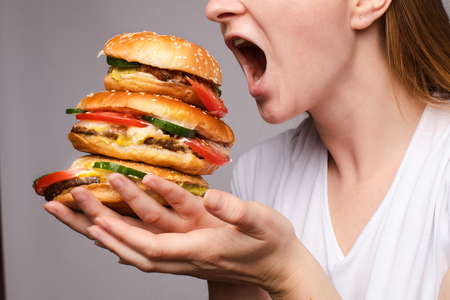 The woman opened her mouth to eat a hamburgerの写真素材