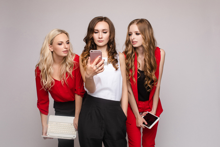 Stylish elegant woman in red suit using tablet with friends.の写真素材
