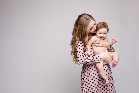 Young mother keeping child on hands and laughingの写真素材