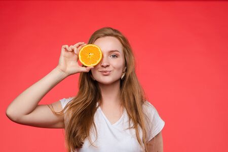 Funny fashionable girl with hairstyle holding oranges on eyes.の写真素材